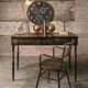 Vintage desk with clock, lamp, and chair against a rustic wooden wall.