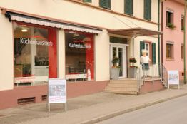 Fassade eines Küchenhauses mit rotem Schaufenster in einer deutschen Straße.