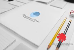 Papelaria com logo da Global Insurance Service, lápis amarelo e preto ao lado.