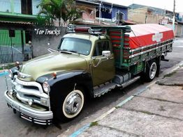 Camión clásico verde y negro estacionado en una calle residencial.