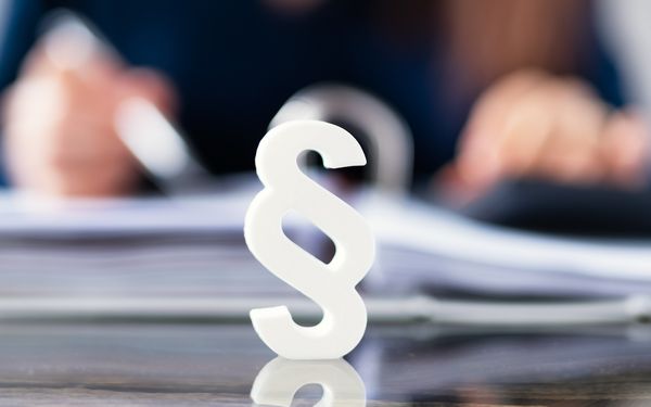 Gesetzzeichen vor einem weißen aufgeklapptem Ordner.