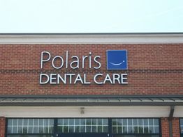 Sign on brick building reading "Polaris Dental Care" with a smiley face logo.