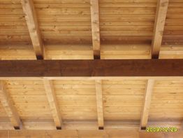 Vista di un soffitto in legno con travi esposte, inquadrato dal basso.