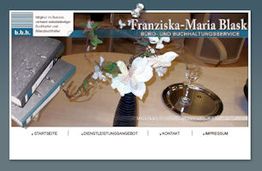 Weiße Blumen in einer Vase auf einem Tisch, daneben Bücher und ein Tablett mit Weinglas.