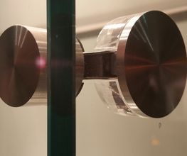 Metallbeschlag an einer gläsernen Duschtür in Nahaufnahme.
