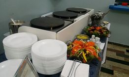 Pilhas de pratos e saladas decorativas ao lado de chapas quentes em um buffet.