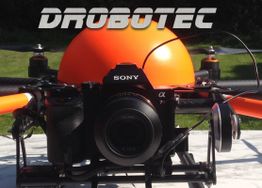 Drohne mit Sony-Kamera, orangefarben, im Freien aufgenommen, "Drobotec" Schriftzug oben.