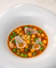 Un plato de guiso colorido con garbanzos, guisantes y cebolla sobre salsa roja.