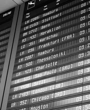 Pantalla de llegadas en el aeropuerto, mostrando vuelos y horas en blanco y negro.