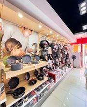 Tienda de utensilios de cocina con estantes llenos de sartenes y ollas. Pared con imagen de familia.