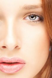 Nahaufnahme eines Frauengesichts mit Fokus auf ein Auge und die Lippen.