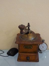 Antike Kaffeemühle auf dem Tisch, daneben eine Computermaus und eine Taschenuhr.