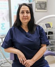 Dentista con uniforme azul oscuro sentada en una clínica dental moderna y equipada.