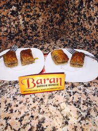 Zwei Teller mit Baklava-Stücken auf granitähnlichem Untergrund, gelbes „Baran Döner House“-Schild.