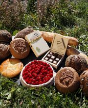 Brot, Schokolade und eine Torte mit roten Beeren auf Gras liegend.