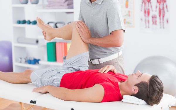 Präventieve Physiotherapie: Physiotherapeut bewegt das Knie eines Patienten