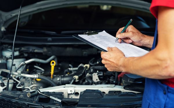 Ein Mechaniker kontrolliert seine Checkliste für die Inspektion eines Autos.