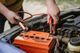 Person attaching jumper cables to a car battery.