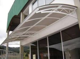 Toldo moderno e curvo em fachada de prédio com janelas de vidro.
