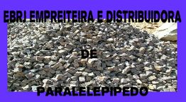 Pilhas de paralelepípedos com texto: "Empreiteira e Distribuidora de Paralelepípedo".