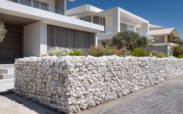 Gabionen vor einem modernen Haus, befüllt mit hellem Steinbruch.
