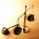 Golden scales of justice and a gavel on a light brown background.