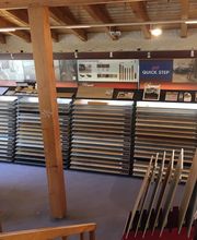 Verkaufsfläche mit Holzfußbodenmustern in Regalen und infoständen, beleuchtet von Deckenstrahlern.