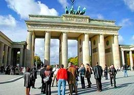 Menschenmenge vor dem Brandenburger Tor in Berlin bei sonnigem Wetter.