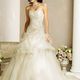 Sposa in abito bianco elegante con gioielli, vicino a colonne e fiori in un interno raffinato.