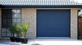 Brick house with a blue garage door and potted plants in front.