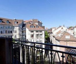 Blick von einem Balkon auf alte europäische Gebäude unter blauem Himmel.
