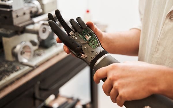 Ein Mann hält eine sensomotorische Armprothese in der Hand