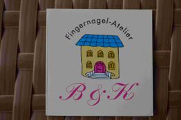 Schild mit der Aufschrift "Fingernagel-Atelier B & K" und einer Zeichnung eines Hauses.