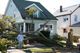 A fallen tree on a house with a man standing nearby, assessing the damage.