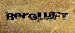 Text "Bergluft" in schwarzer, abgenutzter Schrift auf einer sandfarbenen Oberfläche.