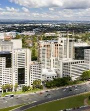 Vista aérea de um complexo de prédios em uma cidade, com céu azul e nuvens esparsas.