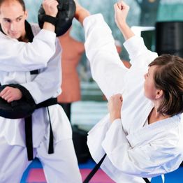 People practicing martial arts in a dojo, wearing white uniforms and black belts.