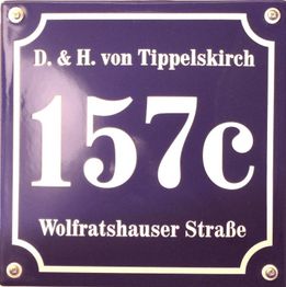 Blaues Metallschild mit weißer Aufschrift: "157c", "D. & H. von Tippelskirch", "Wolfratshauser Straße".