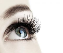 Nahaufnahme eines blauen Auges mit langen Wimpern, das nach oben blickt.