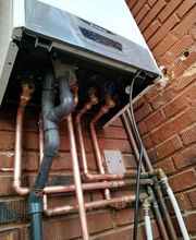 Caldera de gas con tuberías de cobre montada en una pared de ladrillo.