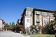 Modern apartment building with trees, clear sky, and geometric sculpture in the foreground.