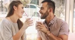 Zwei Personen lächeln sich an und trinken gemeinsam aus Bechern mit Strohhalmen.