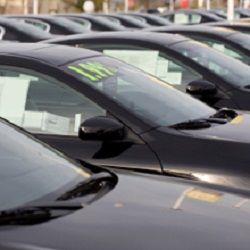 Row of black cars parked in a dealership lot.