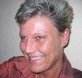 Eine lächelnde Person mit kurzen, grauen Haaren im Profil vor einem hellen Hintergrund.