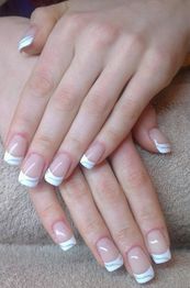 Nahaufnahme von Händen mit eleganter French Maniküre auf einem Handtuch.