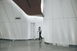 Person cleaning a modern, spacious corridor with curved white walls.