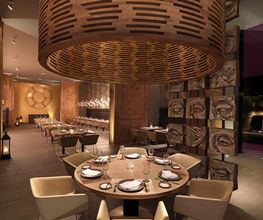 Restaurante con mesas elegantes, decoración de madera y luces cálidas, ambiente acogedor.