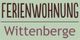 Text auf grünem Hintergrund: "FERIENWOHNUNG Wittenberge".