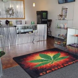 Cannabis store interior with a display counter and a large cannabis leaf rug on the floor.