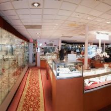 Jewelry store interior with glass display cases and red carpeted floor.